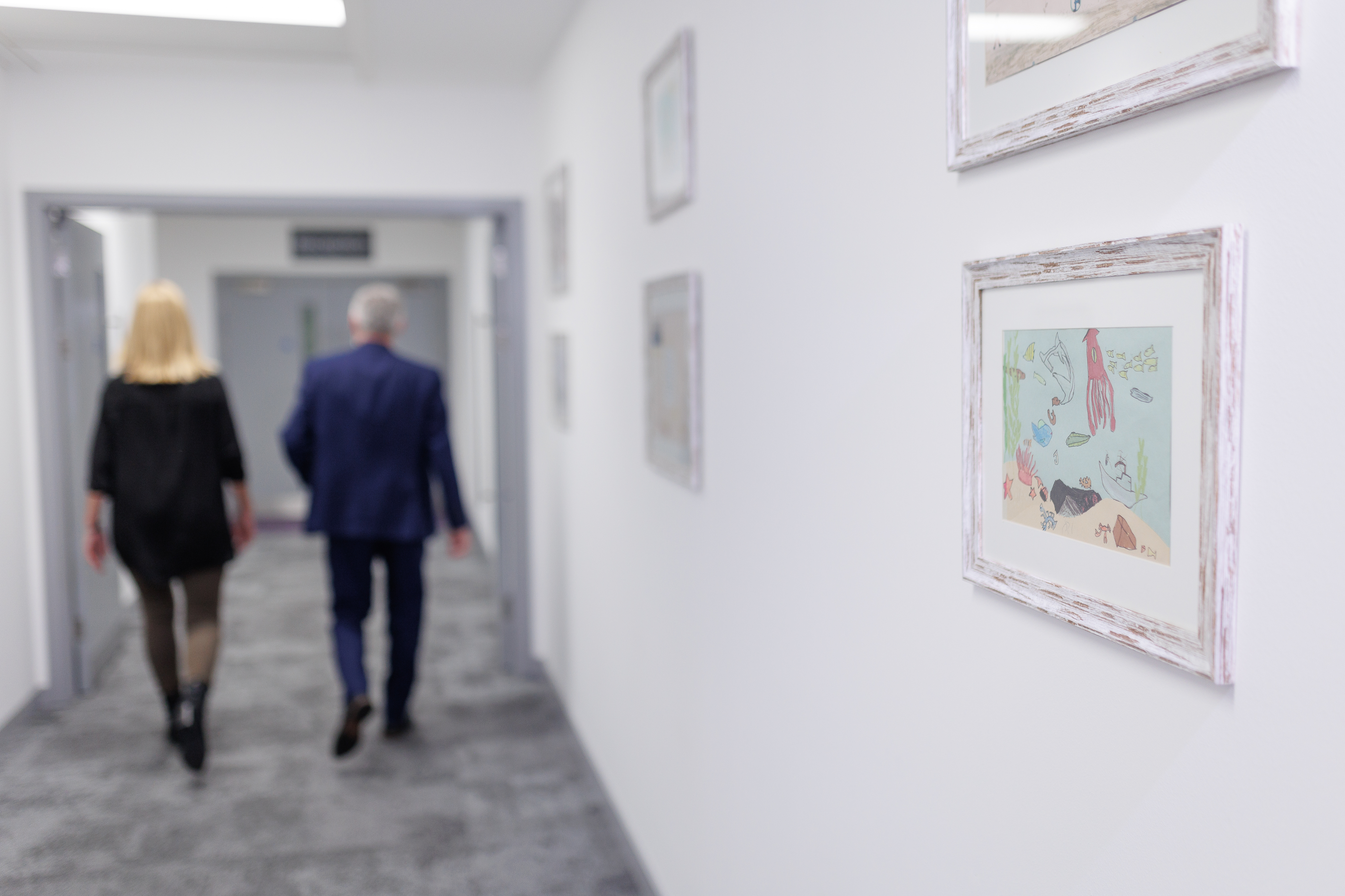 Picture of 2 people walking down a corridor